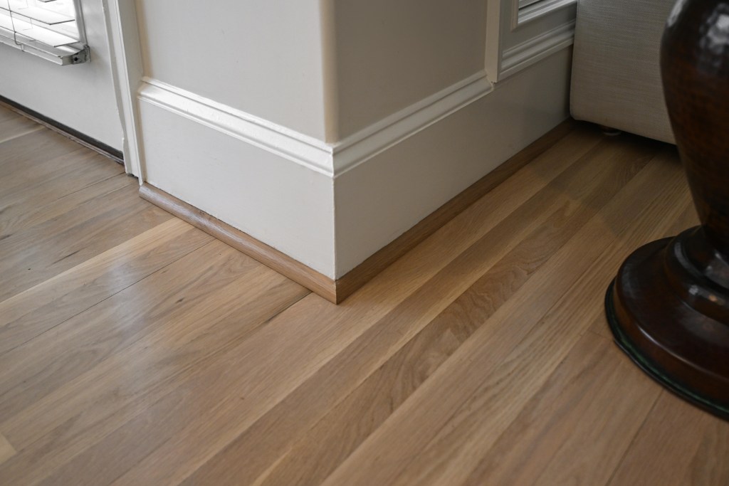 New white oak quarter round finished to match the refinished NordicSeal floor — Hoschton, GA