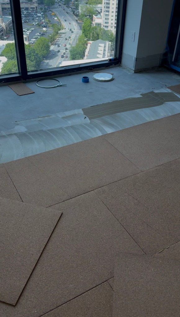 Crew setting Roberts Natural Cork panels with Wakol MS 260 adhesive on the prepared concrete slab in a Buckhead high-rise.