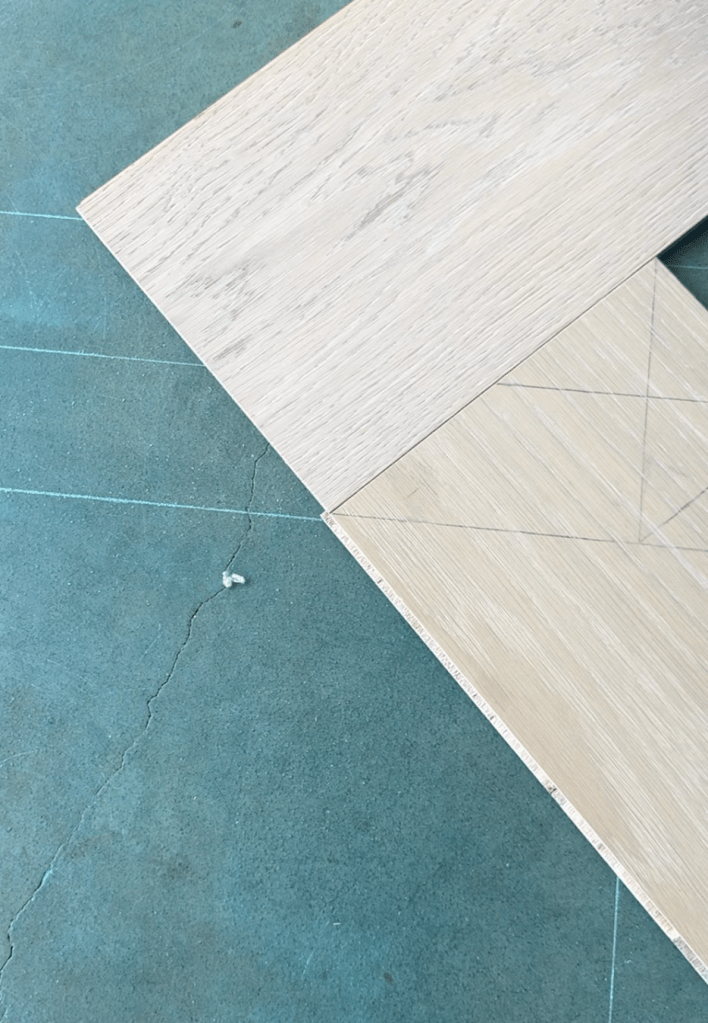 Laser measurement and reference line setup before custom herringbone and border installation with prefinished engineered oak flooring in Atlanta