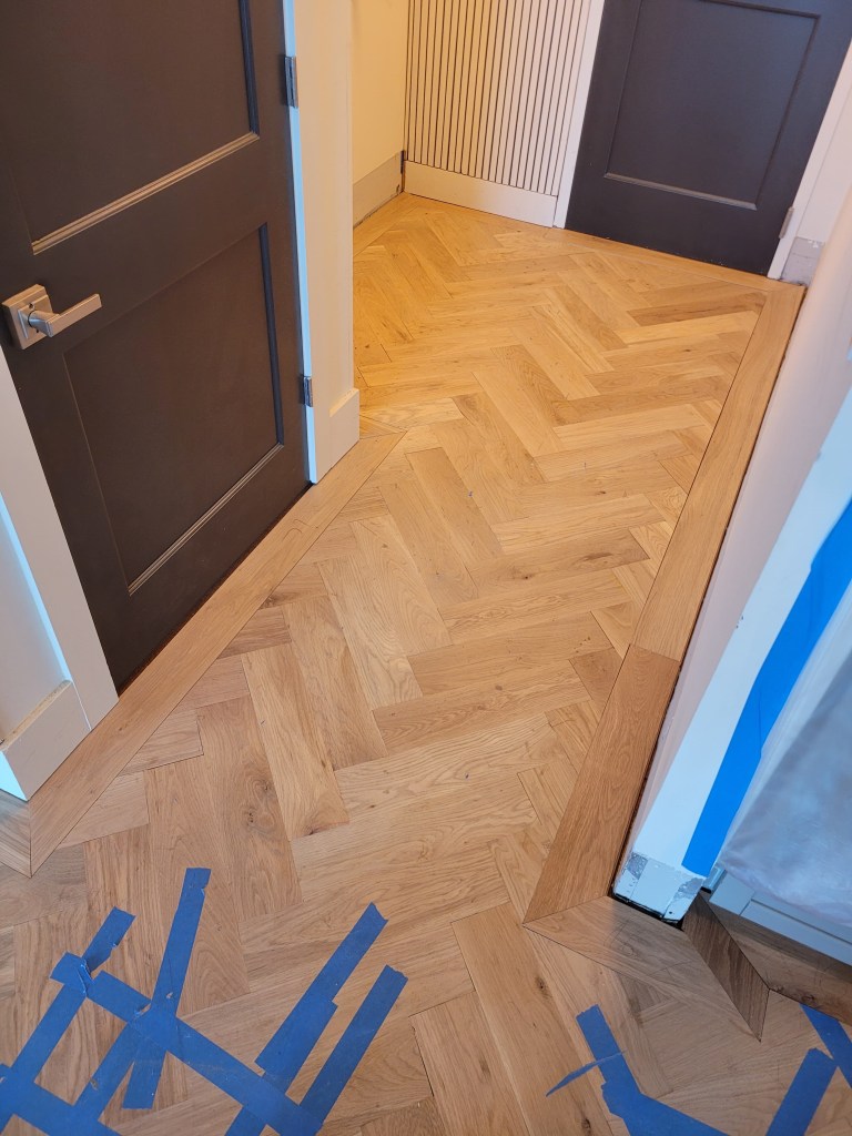 White oak herringbone and 7-inch border at the entrance of a Buckhead high-rise, fitted to the doorway.