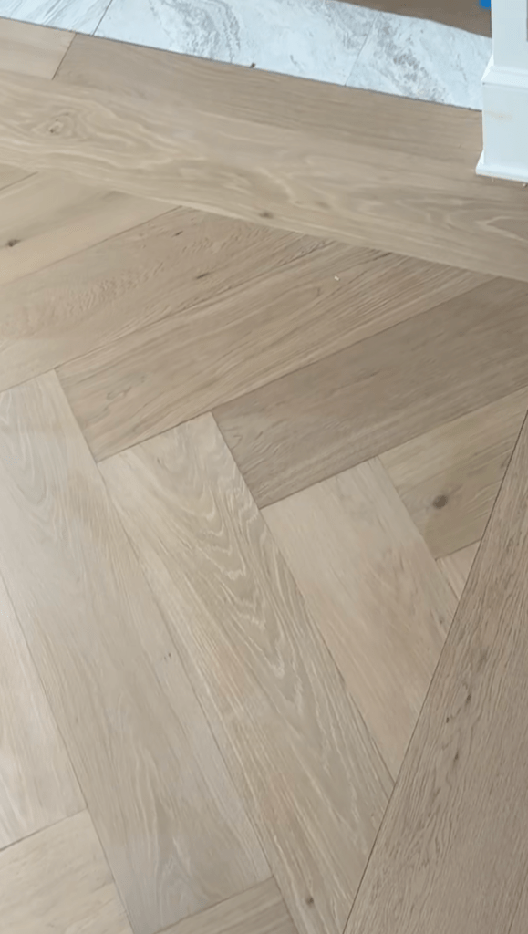 Custom herringbone installation with tongue-and-groove border using prefinished engineered oak flooring in an Atlanta dining room, adapted from straight-layout material with bevel-edge detail