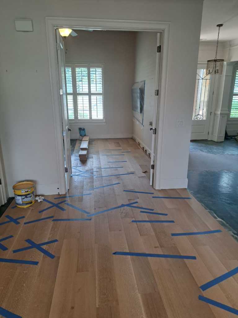 Engineered hardwood installation in progress — concrete slab visible in adjacent room, Chateau Elan, Braselton GA