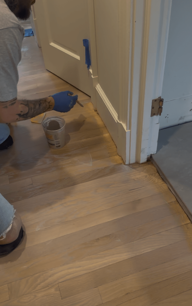 Applying Rubio Monocoat Oil Plus 2C in Linen at doorway transition during Buckhead white oak floor refinishing.