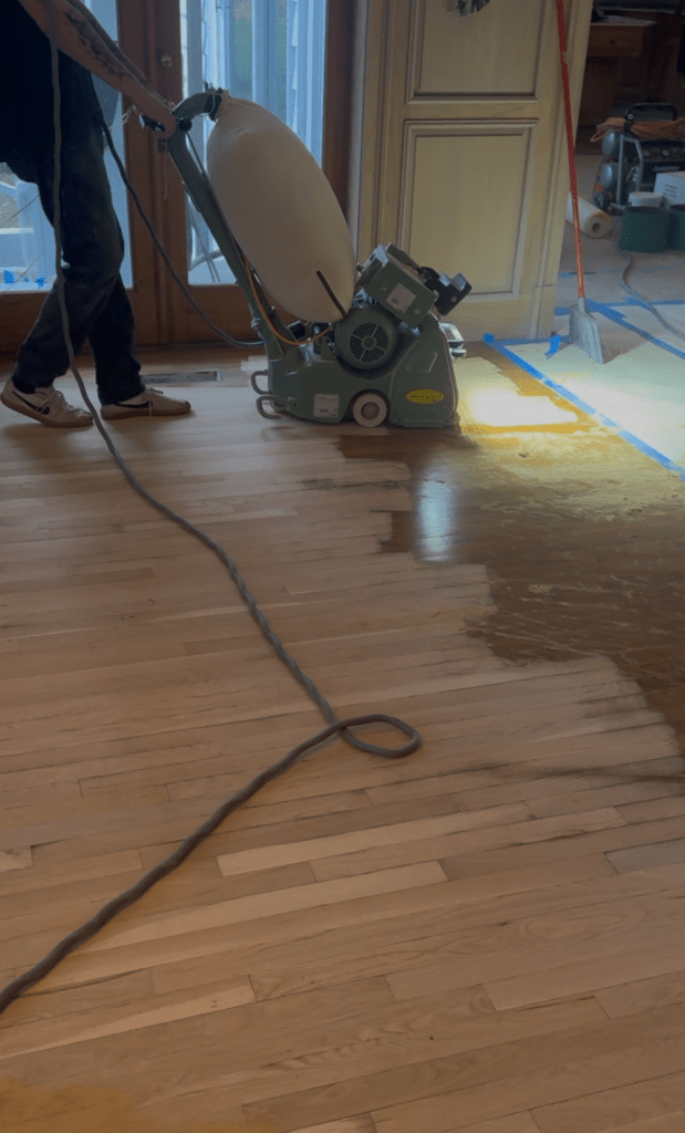 FG Floortec belt sander mid-pass on white oak floor during Buckhead refinishing project.