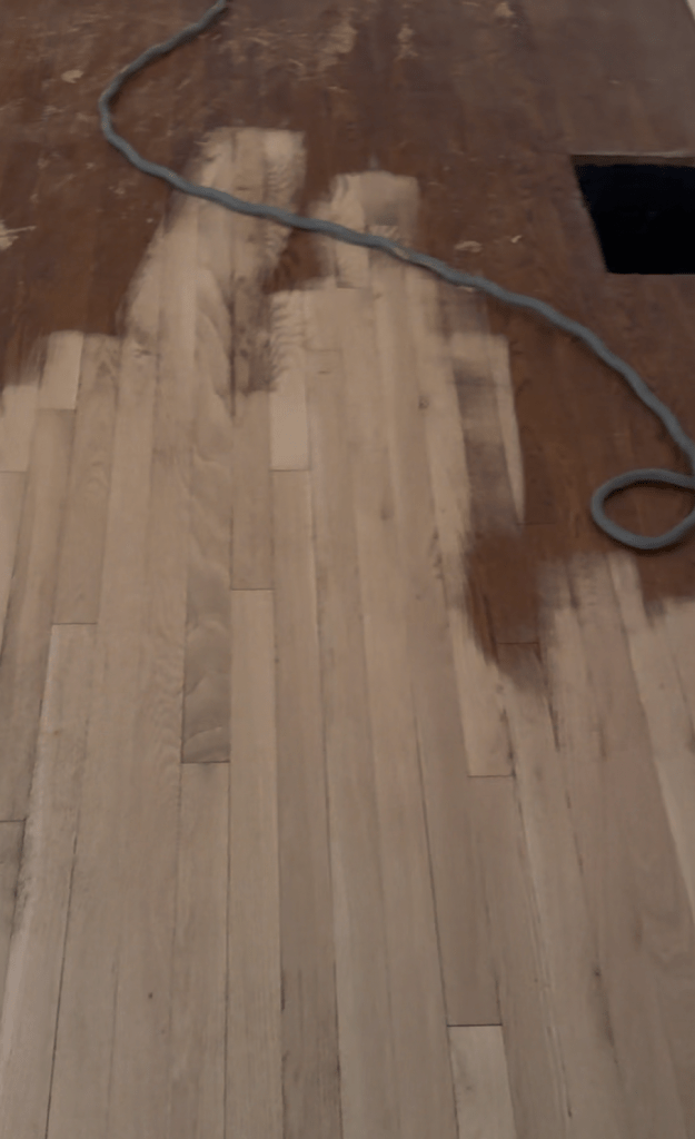 White oak floor mid-sanding, transition between sanded and unsanded sections during Buckhead refinishing project.