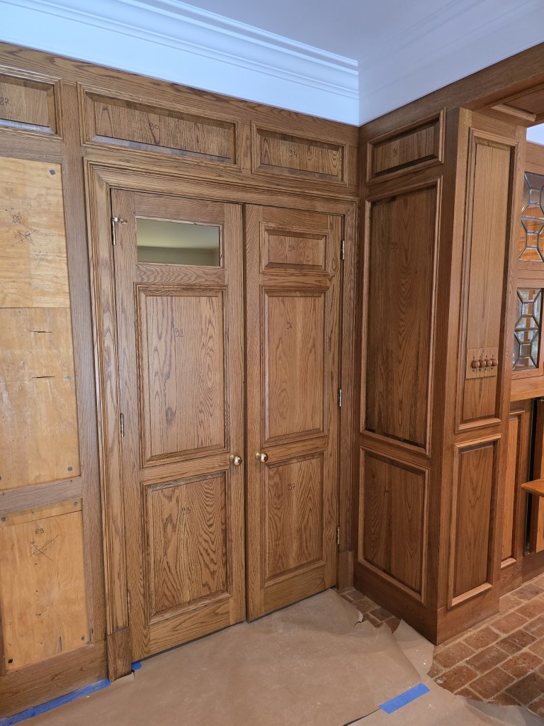 Original orange-toned oak raised paneling before refinishing — Buckhead great room fireplace wall