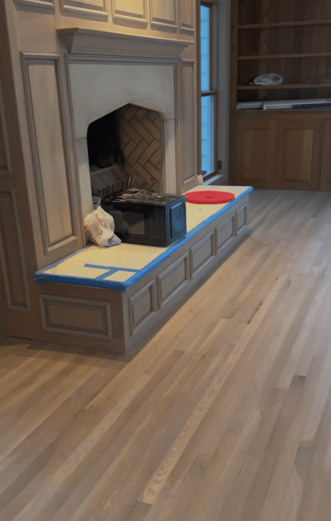 Finished white oak floor refinished with Rubio Monocoat Oil Plus 2C in Linen, shown at the fireplace and built-in bench in a Buckhead home.