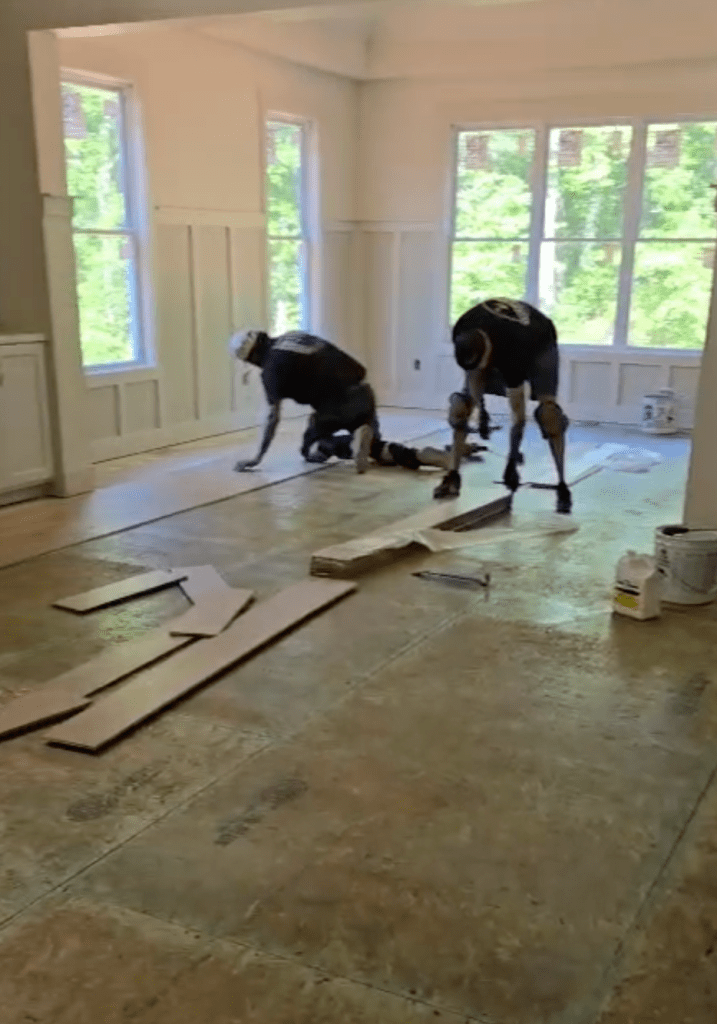 Two Classy Flooring ATL installers setting the starting rows of RW Floors Kells European white oak in a Canton, GA home, working on the Wakol PU 280 primed plywood subfloor with loose planks staged nearby