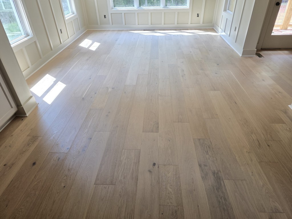 Finished RW Floors Kells European white oak flooring in a living room in Canton, GA, with board-and-batten wainscoting on the walls and windows casting sunlight across the wire-brushed planks