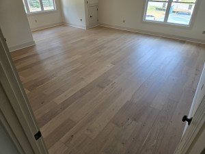 Finished RW Floors Kells European white oak flooring in a large bedroom in Canton, GA, viewed from the doorway with two windows on the far wall and an interior door to the right