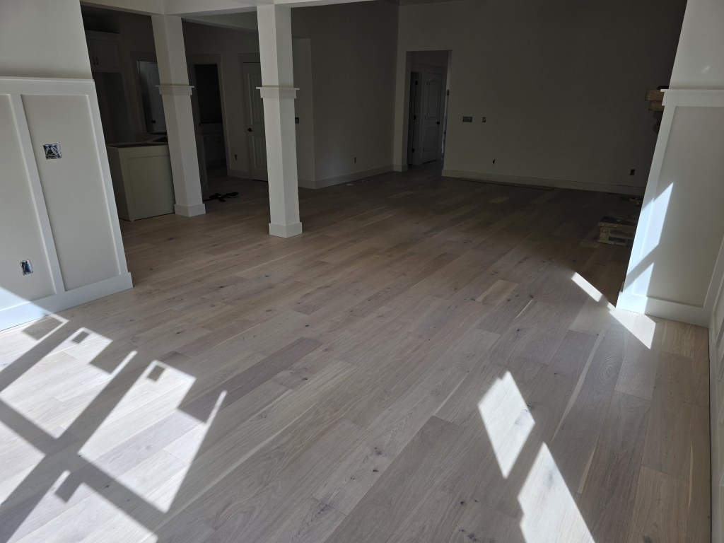 Finished RW Floors Kells European white oak flooring running across the open main level of a Canton, GA home, with square columns framing the transition between the living area and kitchen