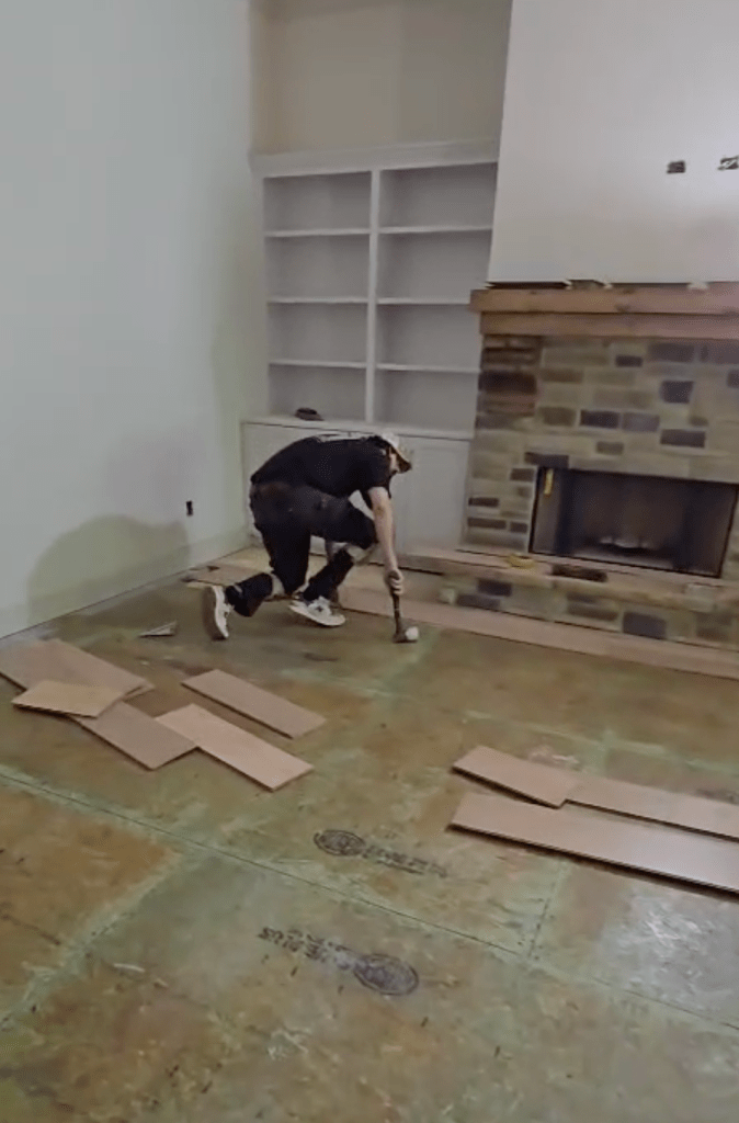 Classy Flooring ATL installer setting a row of RW Floors Kells European white oak flooring near the stone fireplace and white built-ins in a Canton, GA home
