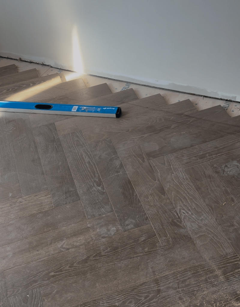 Herringbone field laid with ends running long before the border line is cut, during engineered hardwood installation