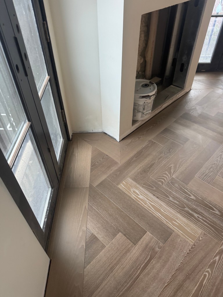 Custom 7-inch border framing the herringbone field along a penthouse window wall in European Ash