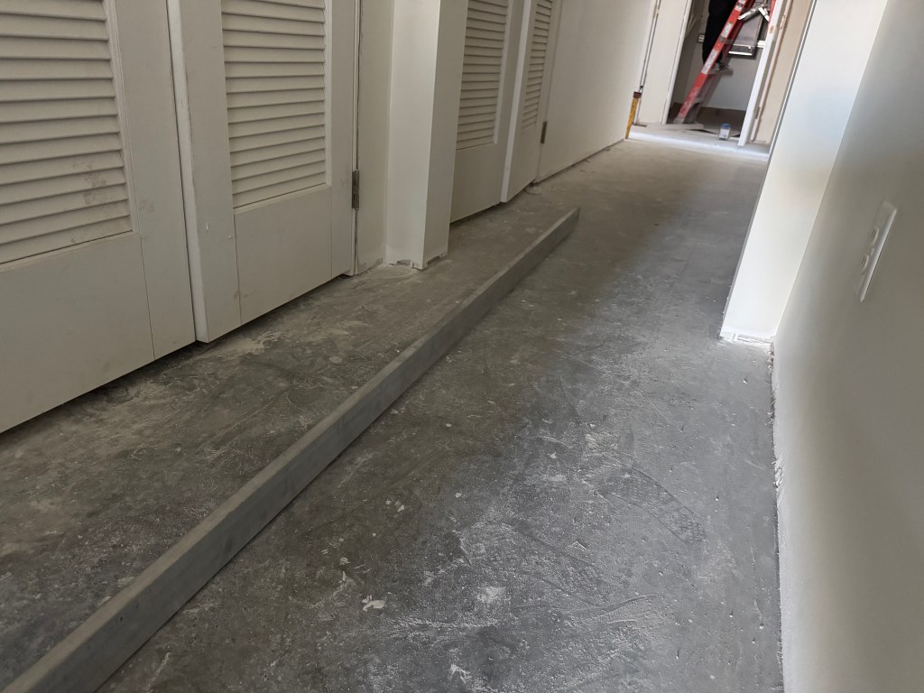 Bare concrete slab in a penthouse hallway before engineered hardwood installation