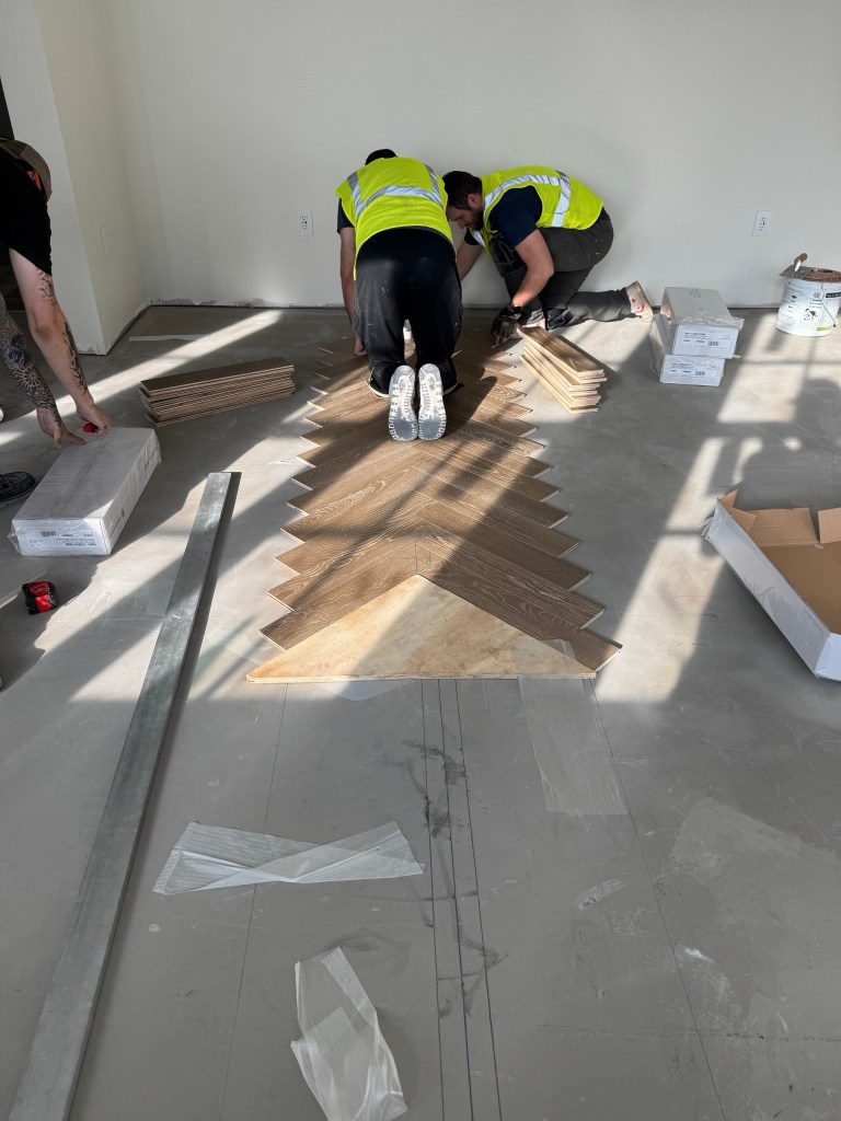 Classy Flooring ATL installers building the herringbone field together during engineered hardwood installation in a Savannah penthouse