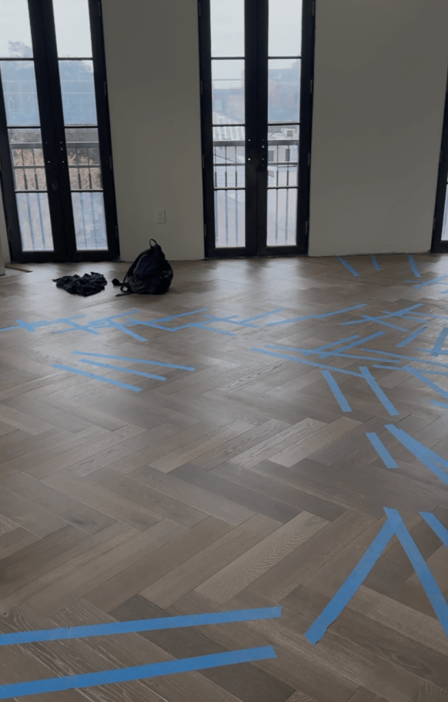 Herringbone field laid across a Savannah penthouse room with floor-to-ceiling windows and protective tape down during installation