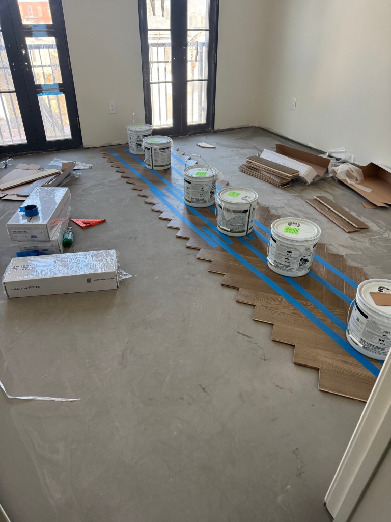 First line of herringbone set on the working line with material staged on the bare slab during installation in a Savannah penthouse