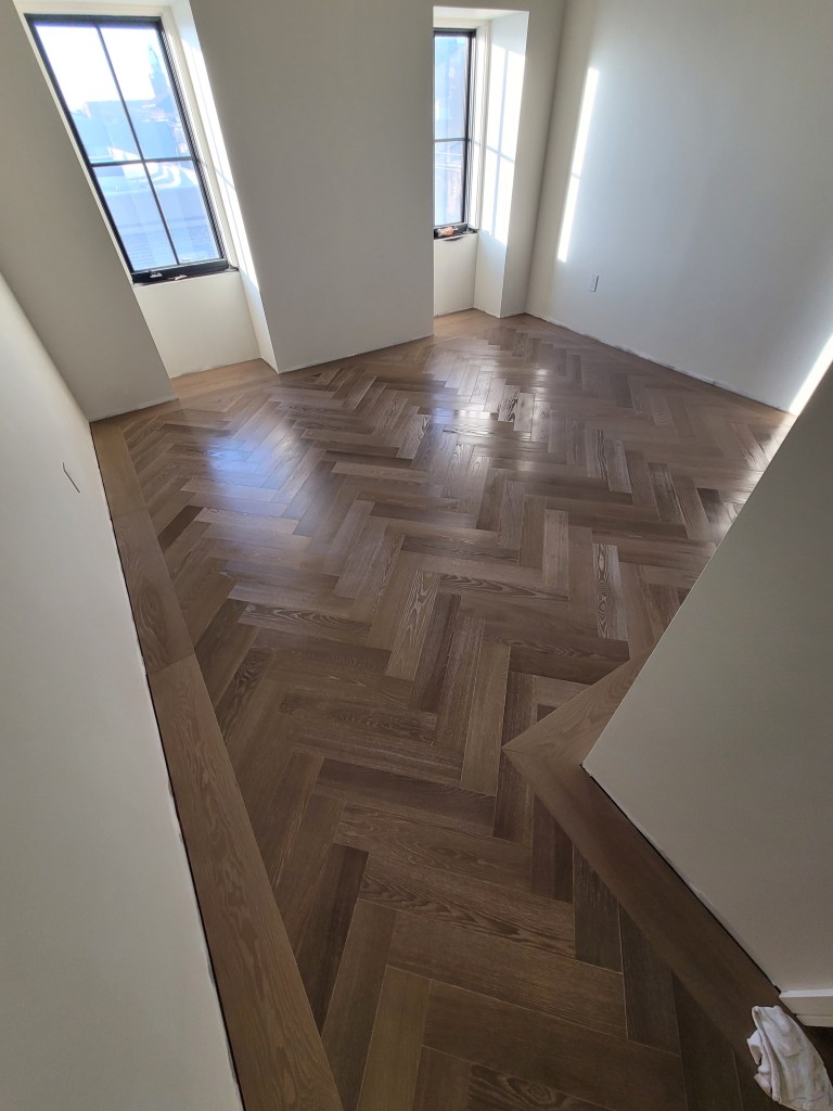Finished European Ash herringbone floor with border in a Savannah penthouse room with two windows