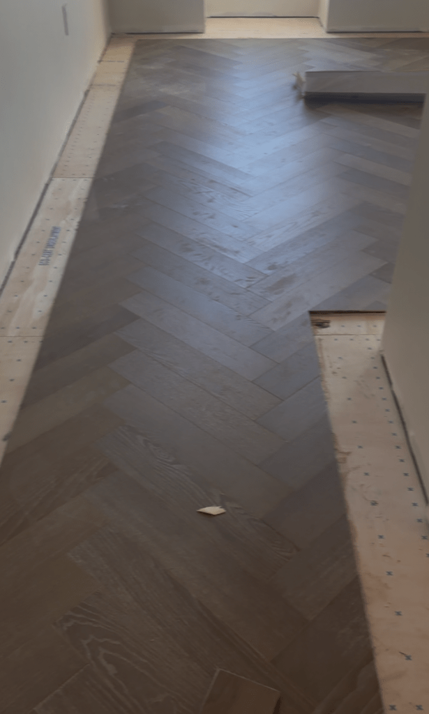Herringbone field laid down the center of a room with open border perimeter on both sides over the underlayment