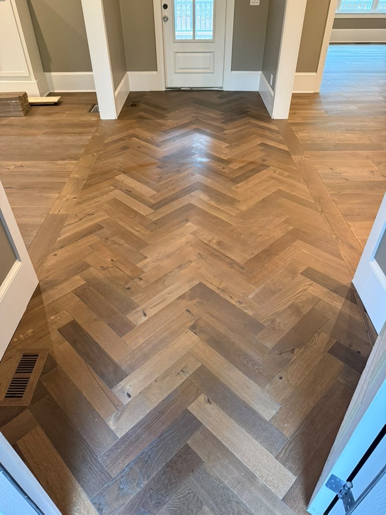 Finished fabricated engineered herringbone entrance with tongue-and-groove border and a color-matched flush-mount vent in Dunwoody, GA
