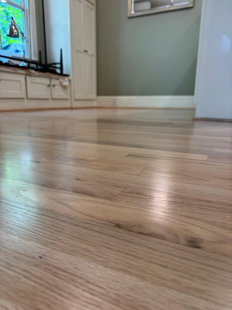 Close-up of finished red oak floorboards in Atlanta showing grain and mineral streaks under a neutral satin finish, no pink undertone