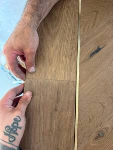 Classy Flooring ATL installer fitting a border piece by hand alongside the brass inlay in the European white oak floor
