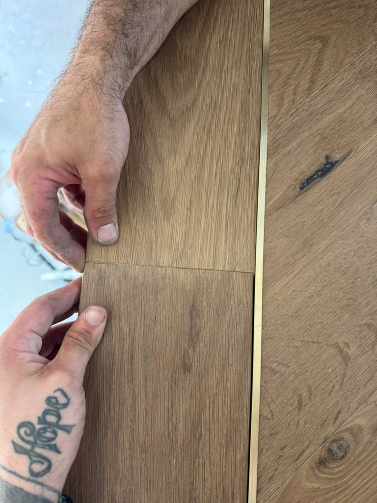 Classy Flooring ATL installer fitting a border piece by hand alongside the brass inlay in the European white oak floor