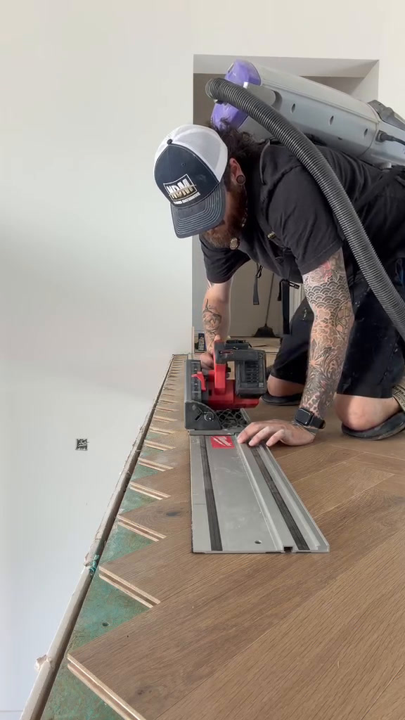 Classy Flooring ATL installer making the final perimeter cut in the European white oak herringbone field with a dust-extracted track saw on the Woodstock estate catwalk.