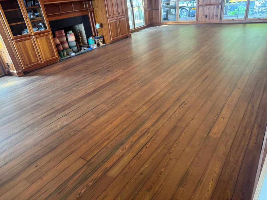 Reclaimed heart pine flooring in DuraSeal Jacobean running the full length of the living room toward the fireplace and built-in cabinetry, Big Canoe, Georgia