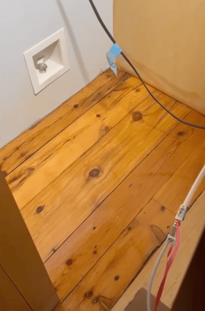 Deep golden-amber heart pine flooring preserved beneath a refrigerator, showing the original colour of the floor, Roswell, Georgia