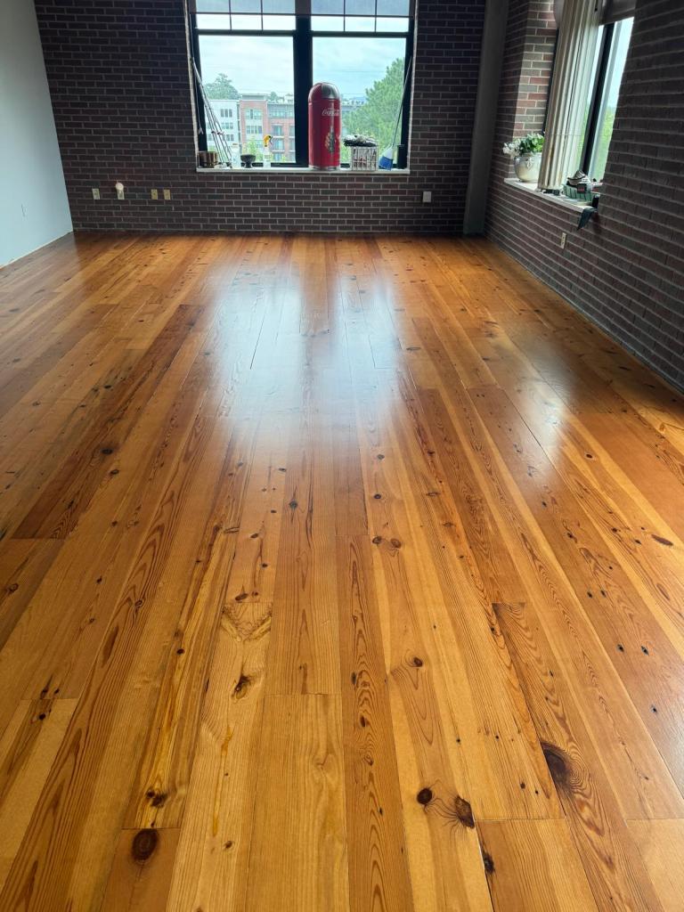 Wide-plank heart pine floor refinished to a warm amber tone, brick interior walls and black-framed windows, Roswell, Georgia