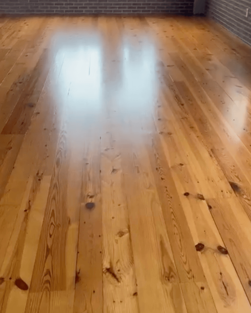 Refinished heart pine floor with window light reflected across the boards, the reflection holding its shape on a flat surface, Roswell, Georgia