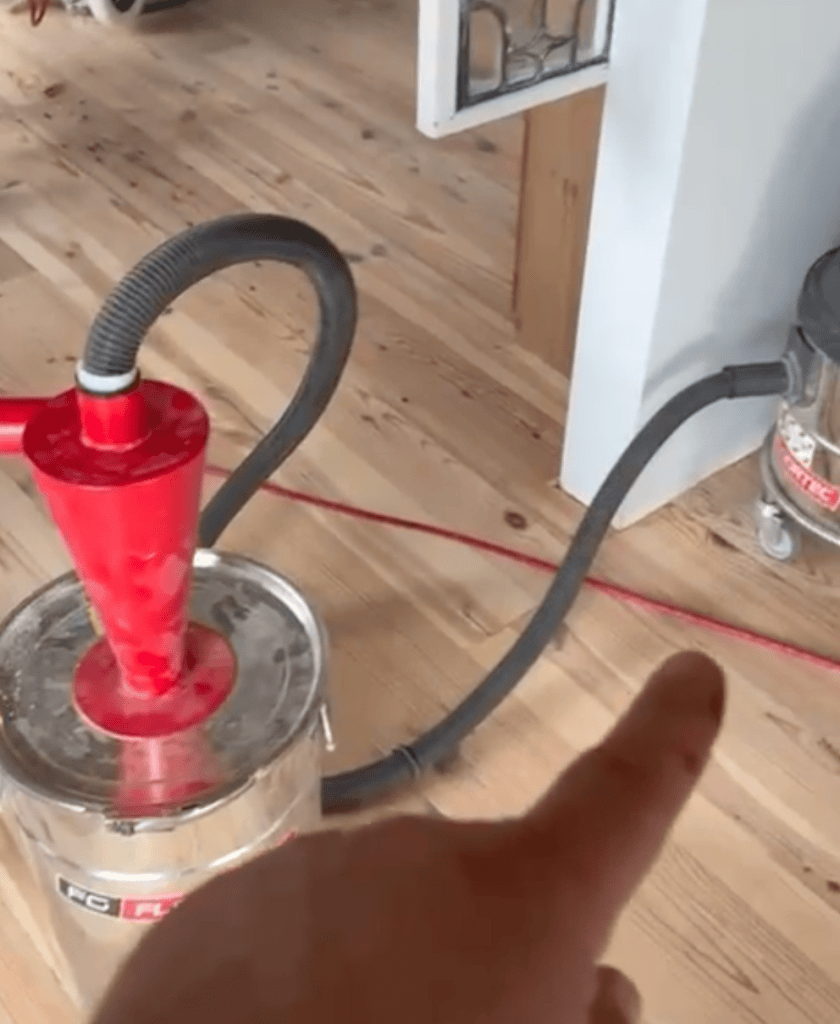 Cyclone dust separator and collection drum connected by hose to sanding equipment on a heart pine floor, Roswell, Georgia