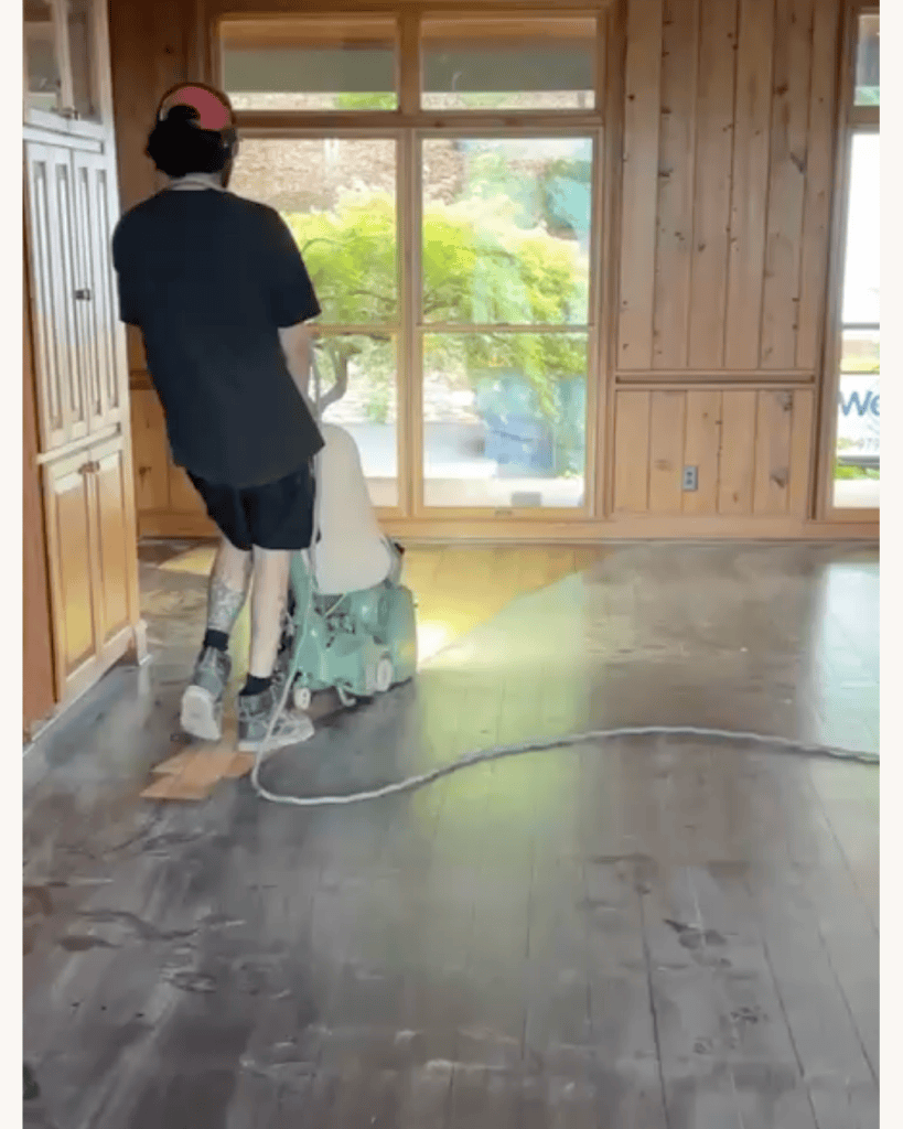 Classy Flooring ATL crew member taking the first sanding cut on reclaimed heart pine flooring with a belt sander, Big Canoe, Georgia