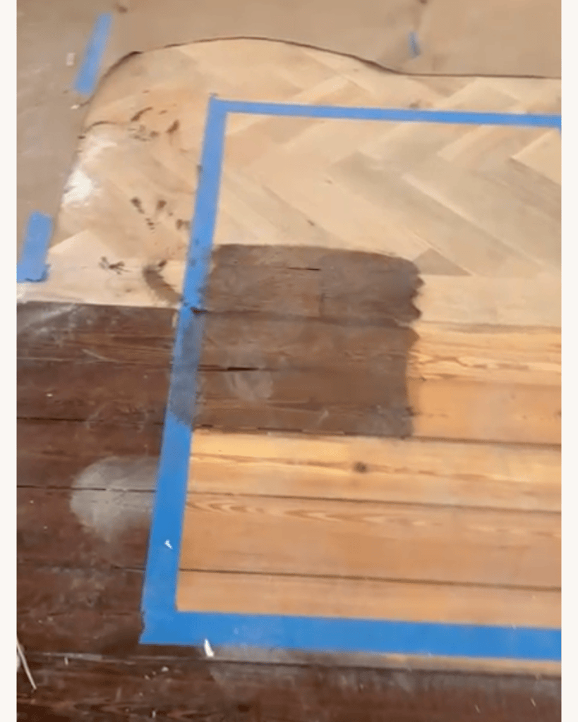 Taped stain sample applied across the junction between white oak herringbone and pine plank flooring, Big Canoe, Georgia