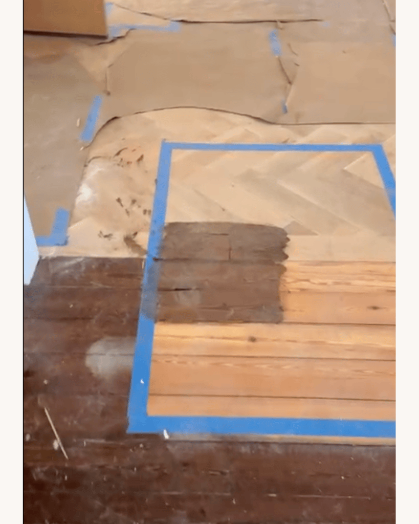 Stain sample taped out at the junction of white oak herringbone and pine plank flooring with masking paper protecting the herringbone, Big Canoe, Georgia