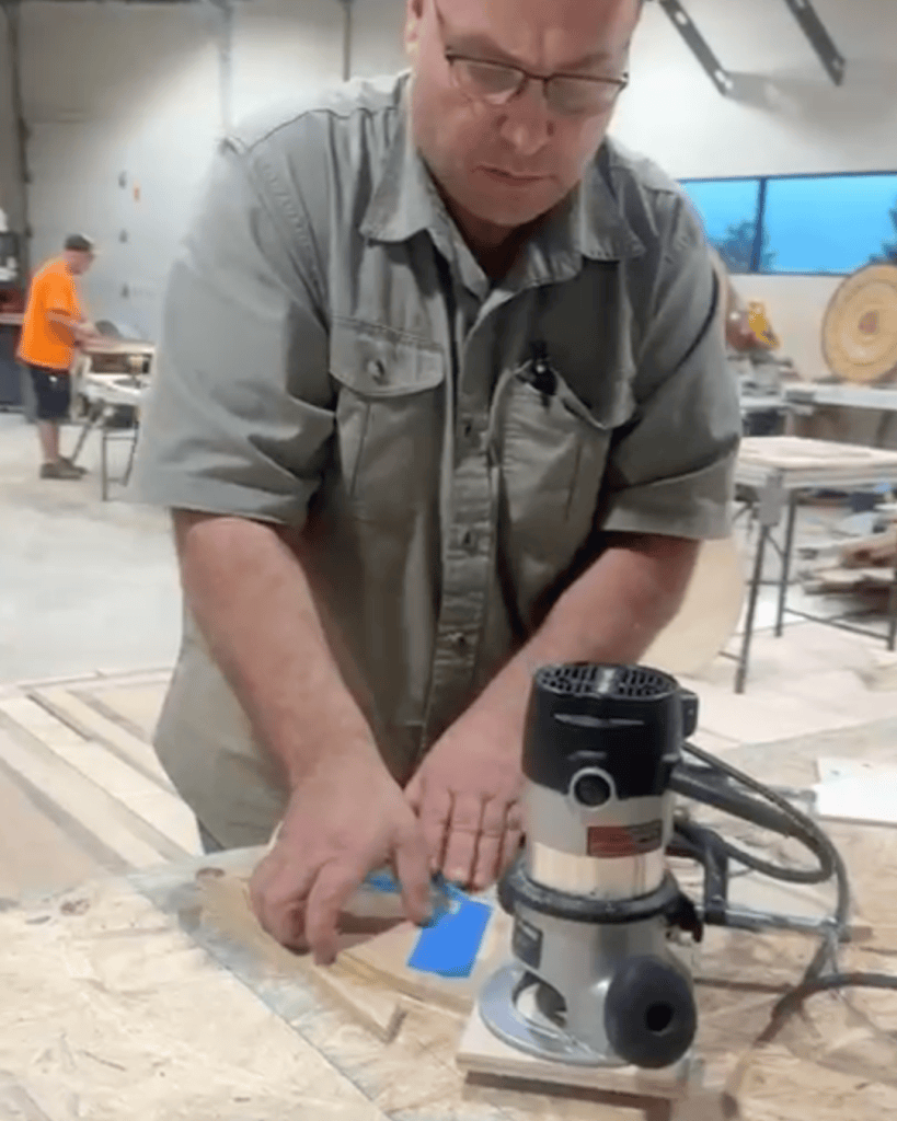 Claudiu Toma of Classy Flooring ATL using a router at a workbench during the NWFA Precision Patterns: Medallions course in St. Louis, Missouri